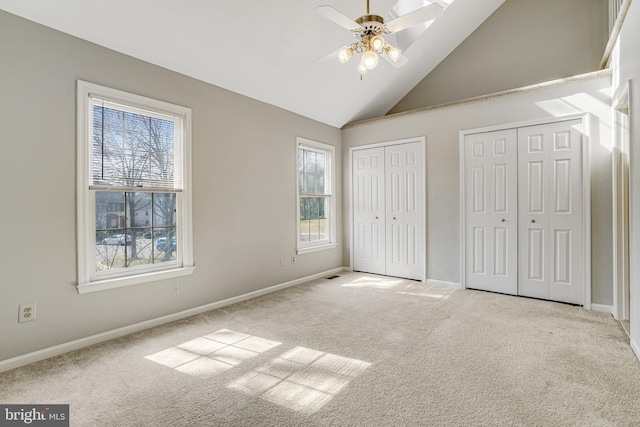 unfurnished bedroom featuring carpet floors, high vaulted ceiling, two closets, and baseboards