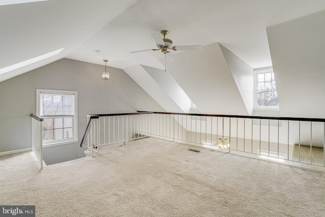 additional living space featuring carpet floors, lofted ceiling with skylight, ceiling fan, and visible vents