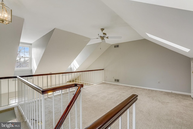 additional living space featuring carpet floors, visible vents, lofted ceiling with skylight, a ceiling fan, and baseboards