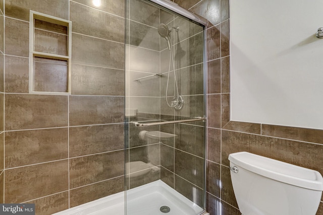 bathroom featuring a stall shower, tile walls, and toilet