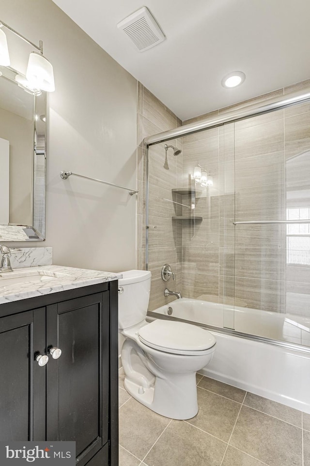 bathroom with visible vents, bath / shower combo with glass door, toilet, tile patterned flooring, and vanity