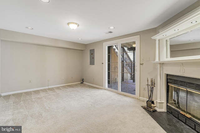 unfurnished living room featuring carpet, visible vents, a fireplace with flush hearth, electric panel, and baseboards