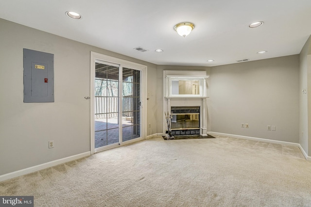 unfurnished living room featuring carpet floors, visible vents, a fireplace with flush hearth, electric panel, and baseboards