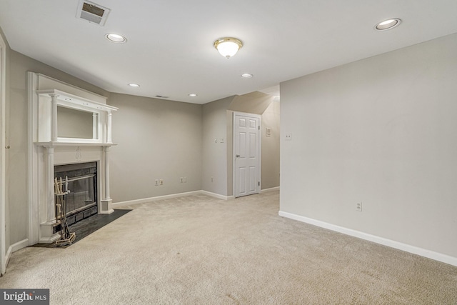 unfurnished living room with carpet floors, recessed lighting, visible vents, a fireplace with flush hearth, and baseboards