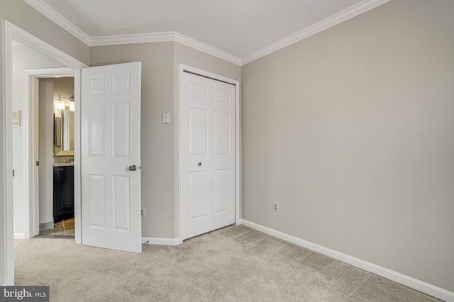 unfurnished bedroom with ornamental molding, a closet, light carpet, and baseboards