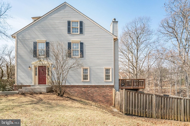 view of front of home featuring a chimney, fence, a front lawn, and a wooden deck