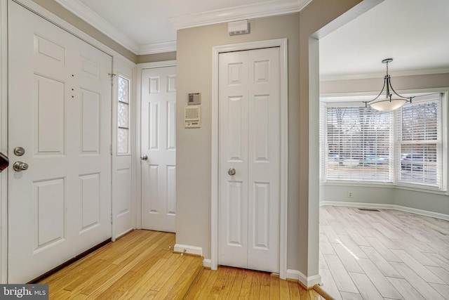 entrance foyer featuring light wood-style flooring, baseboards, and crown molding