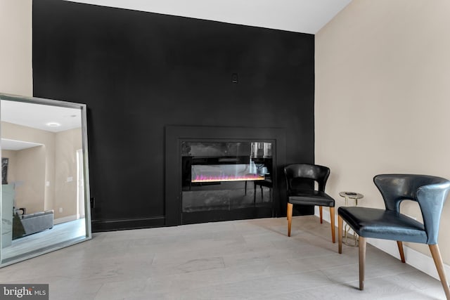 living area featuring a glass covered fireplace and baseboards