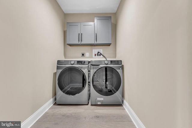 washroom with cabinet space, baseboards, and washer and clothes dryer