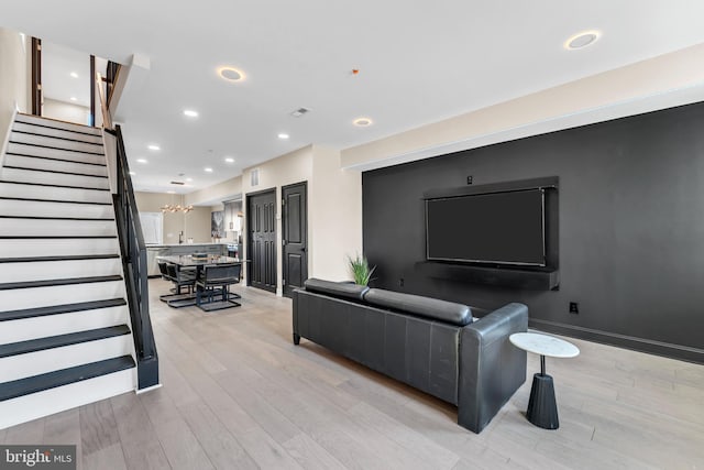 living room featuring stairs, light wood finished floors, baseboards, and recessed lighting