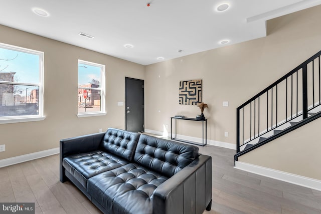 living room featuring visible vents, stairway, baseboards, and wood finished floors