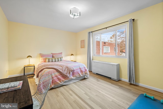 bedroom featuring radiator heating unit, baseboards, and wood finished floors