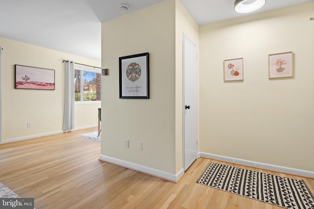 corridor with baseboards and wood finished floors