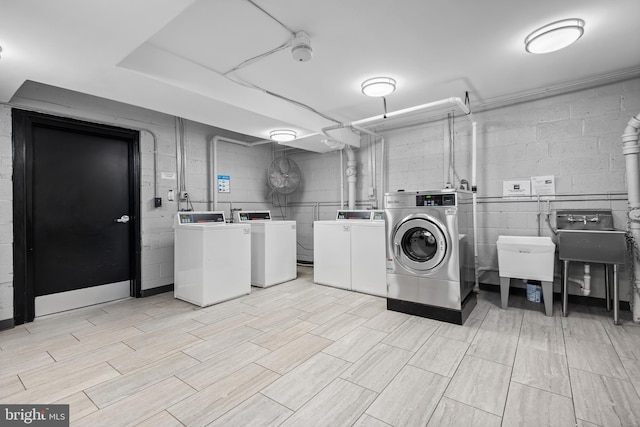 common laundry area with a sink, washing machine and dryer, and concrete block wall