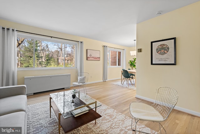 living area with light wood finished floors, radiator heating unit, and baseboards