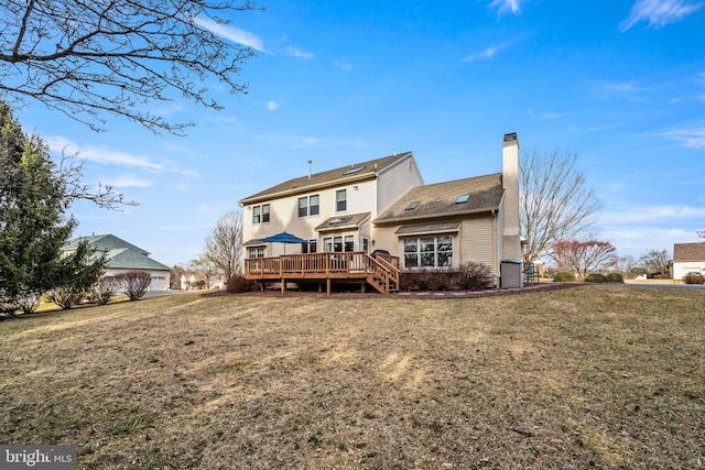 back of property with a chimney, a deck, and a lawn