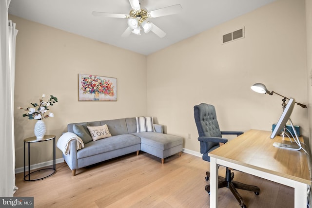 office space featuring a ceiling fan, visible vents, baseboards, and wood finished floors