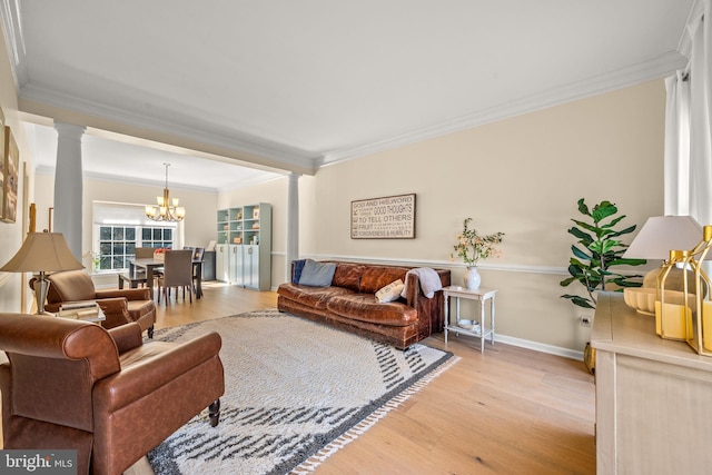 living room with light wood-style floors, a notable chandelier, decorative columns, and crown molding