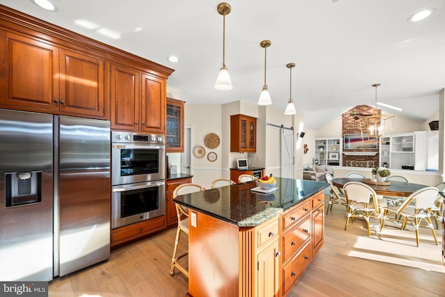 kitchen featuring stainless steel appliances, lofted ceiling, light wood-style floors, and a barn door