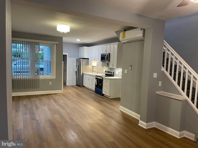 kitchen featuring white cabinetry, appliances with stainless steel finishes, wood finished floors, and a wall mounted AC