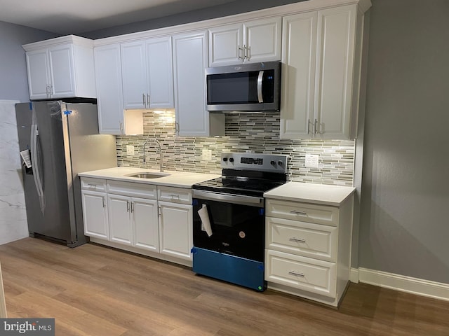 kitchen featuring stainless steel appliances, a sink, white cabinets, light countertops, and light wood-type flooring