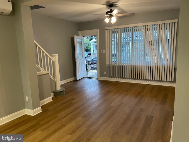 entrance foyer with stairs, a wall unit AC, wood finished floors, and baseboards