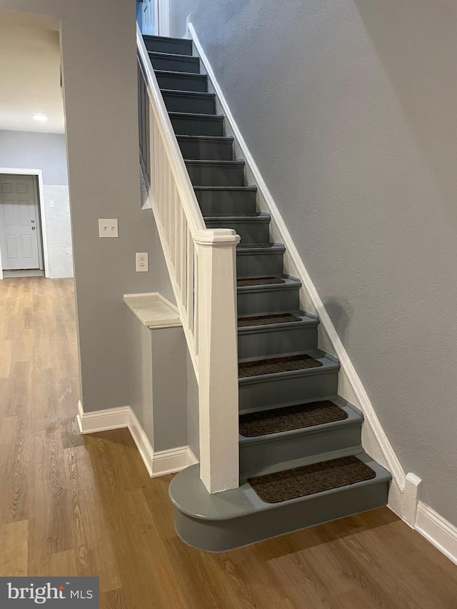 stairway featuring wood finished floors and baseboards