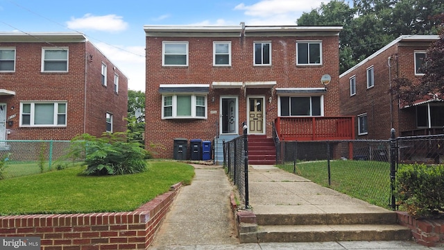 view of front of house featuring brick siding, a front yard, and fence private yard