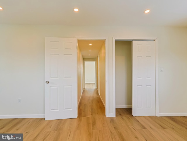 corridor featuring light wood-style floors, baseboards, and recessed lighting