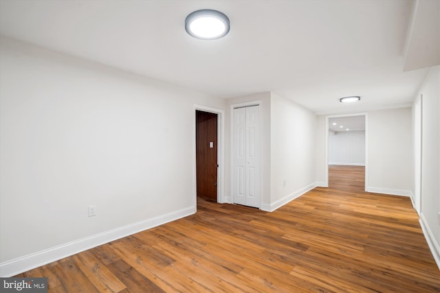 spare room with baseboards and wood finished floors