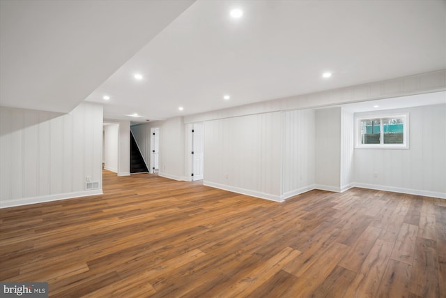 basement featuring wood-type flooring, stairs, baseboards, and recessed lighting