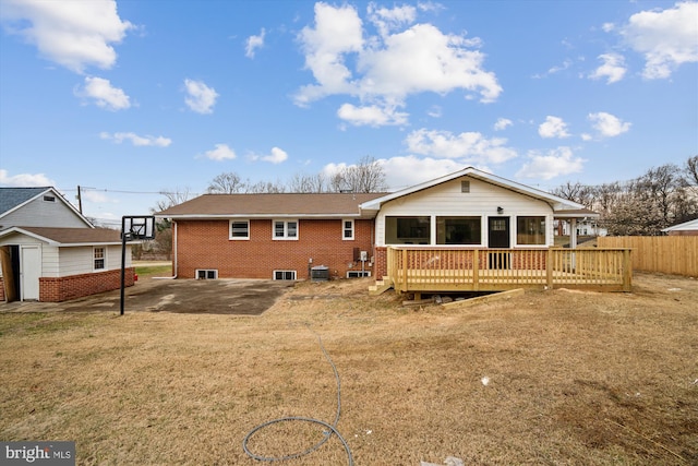 rear view of house with an outbuilding, brick siding, fence, a yard, and a wooden deck