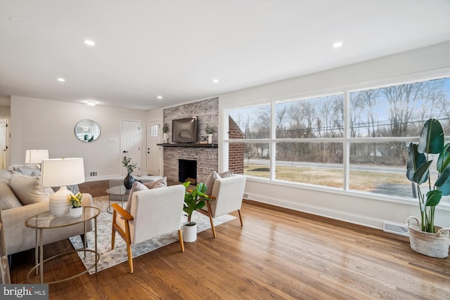 living room with a fireplace, recessed lighting, visible vents, wood finished floors, and baseboards