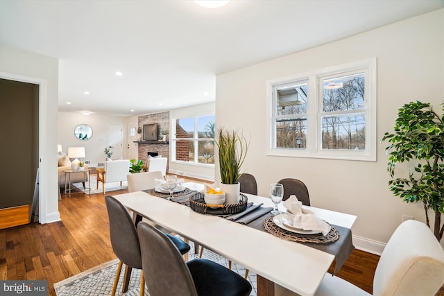 dining space with recessed lighting, a fireplace, wood finished floors, and baseboards