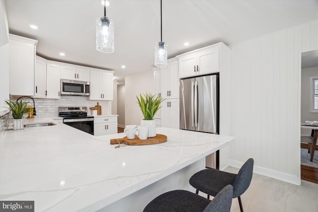 kitchen featuring light stone countertops, appliances with stainless steel finishes, a kitchen breakfast bar, and backsplash