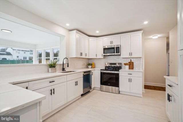 kitchen with stainless steel appliances, white cabinetry, a sink, and decorative backsplash