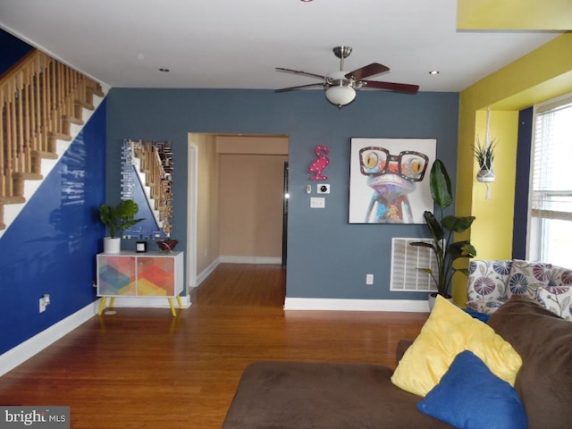 living room with visible vents, stairway, baseboards, and wood finished floors