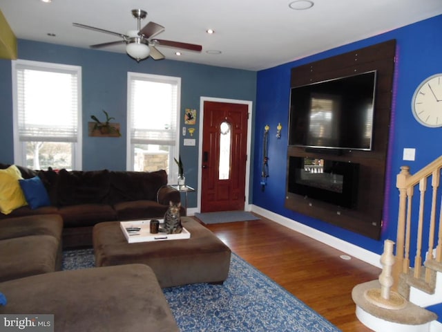 living area with recessed lighting, wood finished floors, a ceiling fan, baseboards, and stairway