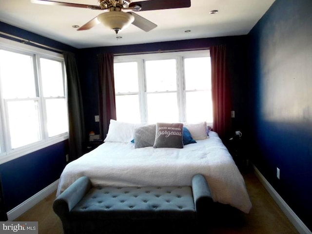 bedroom featuring multiple windows, a ceiling fan, and baseboards