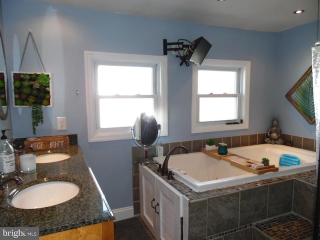 bathroom with a healthy amount of sunlight, a tub with jets, and a sink