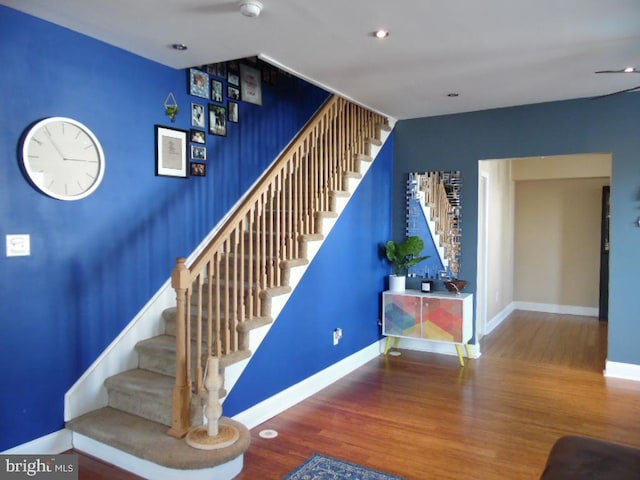 stairs featuring an accent wall, baseboards, and wood finished floors