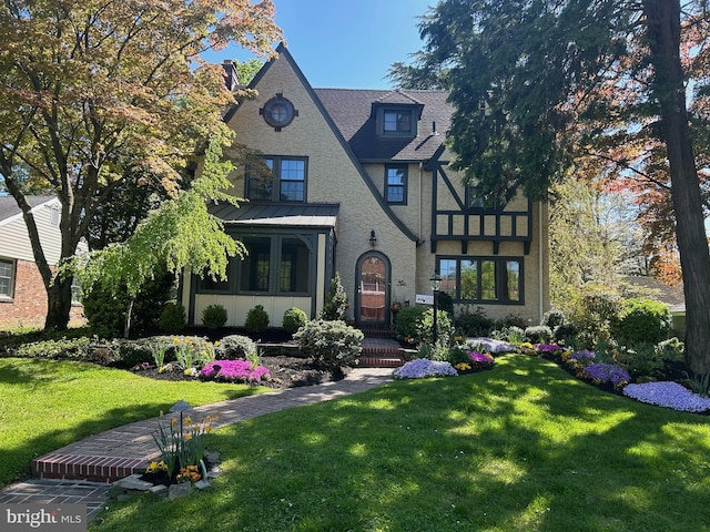 english style home featuring roof with shingles, metal roof, and a front yard