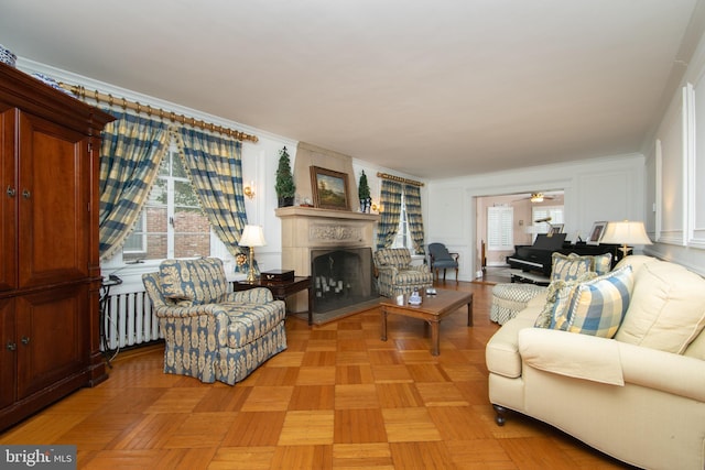 living room featuring ceiling fan, radiator heating unit, and a fireplace