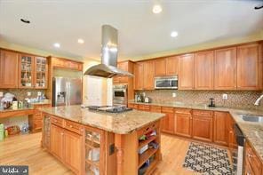 kitchen featuring stainless steel appliances, light stone counters, a kitchen island, and island range hood