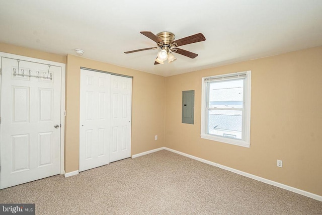 unfurnished bedroom with light carpet, electric panel, baseboards, a ceiling fan, and a closet