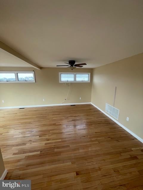 spare room featuring baseboards, visible vents, ceiling fan, wood finished floors, and beamed ceiling