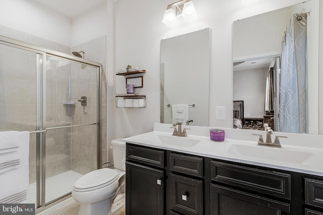 ensuite bathroom with double vanity, a shower stall, and a sink
