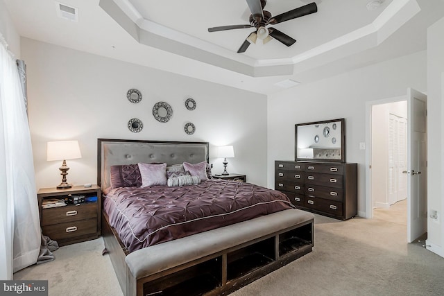 bedroom featuring light carpet, baseboards, visible vents, a raised ceiling, and a ceiling fan