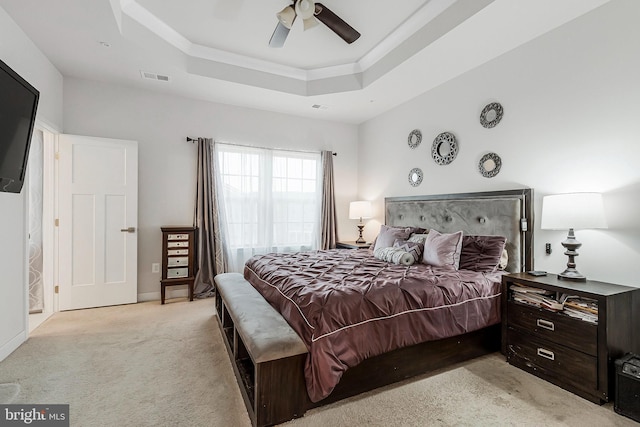 bedroom featuring light carpet, visible vents, a ceiling fan, ornamental molding, and a raised ceiling