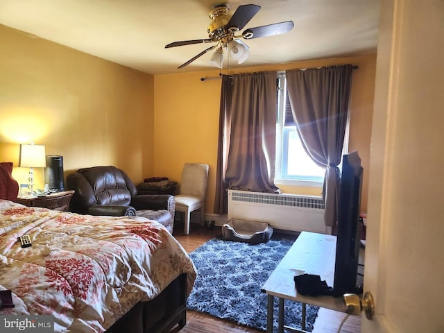 bedroom with wood finished floors, a ceiling fan, and radiator